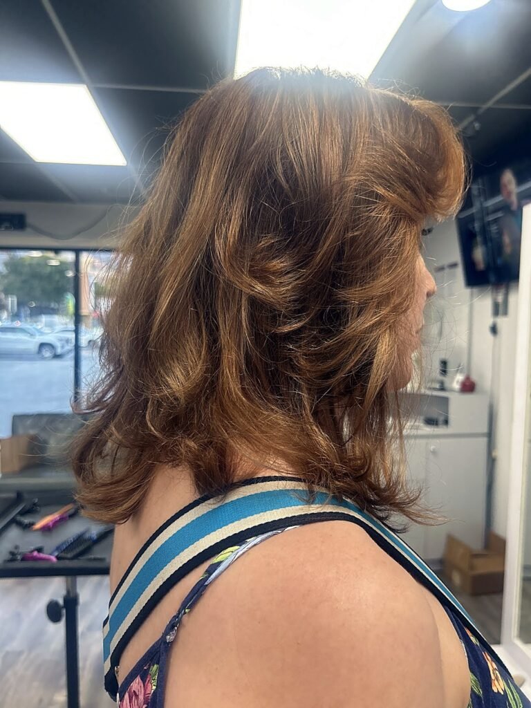 Side view of a layered, shoulder-length cut in warm bronde