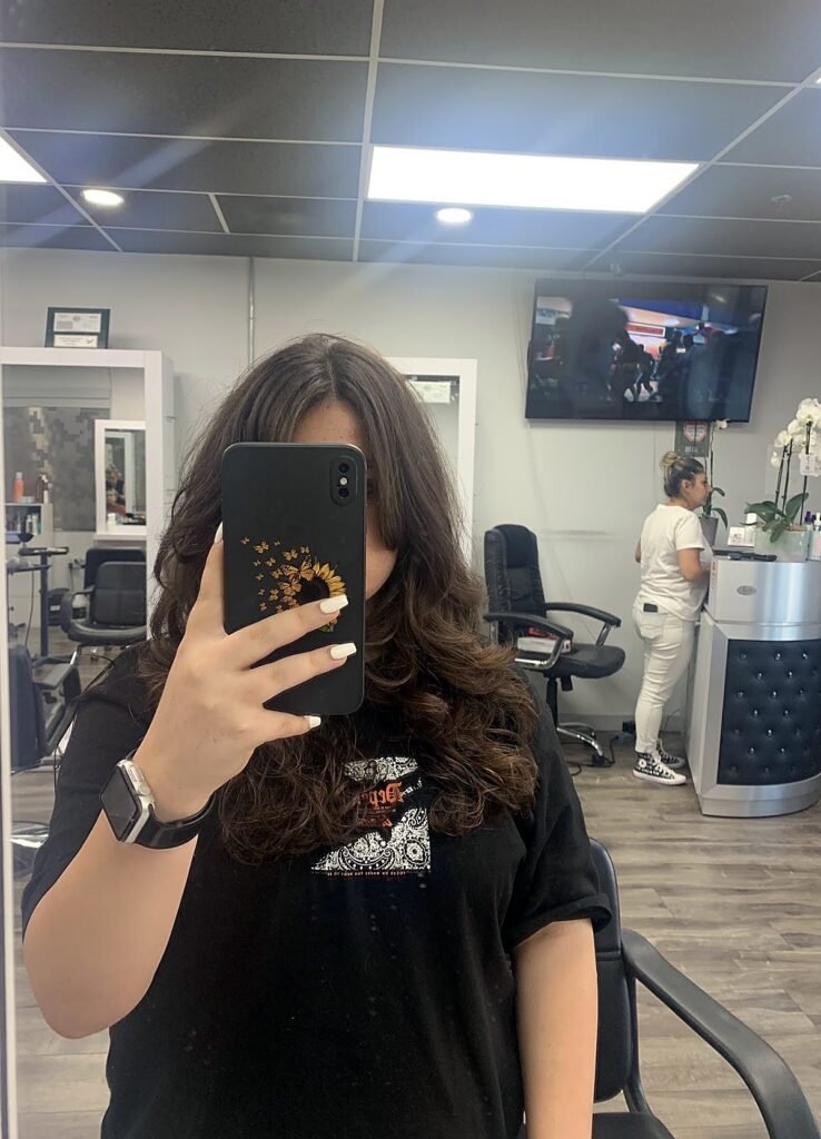 Client in the salon mirror with long brunette waves